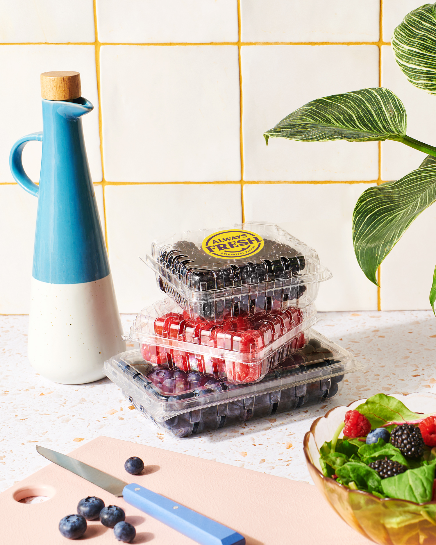 Image of Always Fresh berries in containers stacked on a counter with a mixed berry salad in a bowl