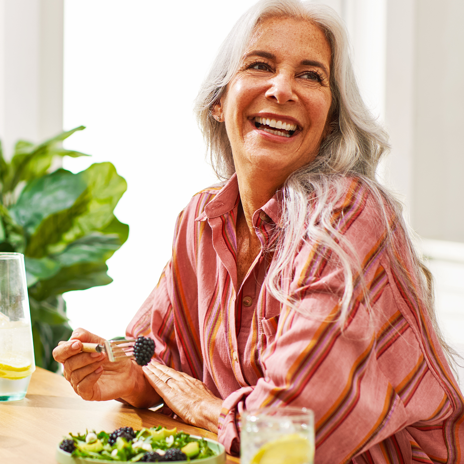 Image of blackberry salad with a woman smiling and a blackberry on her fork.