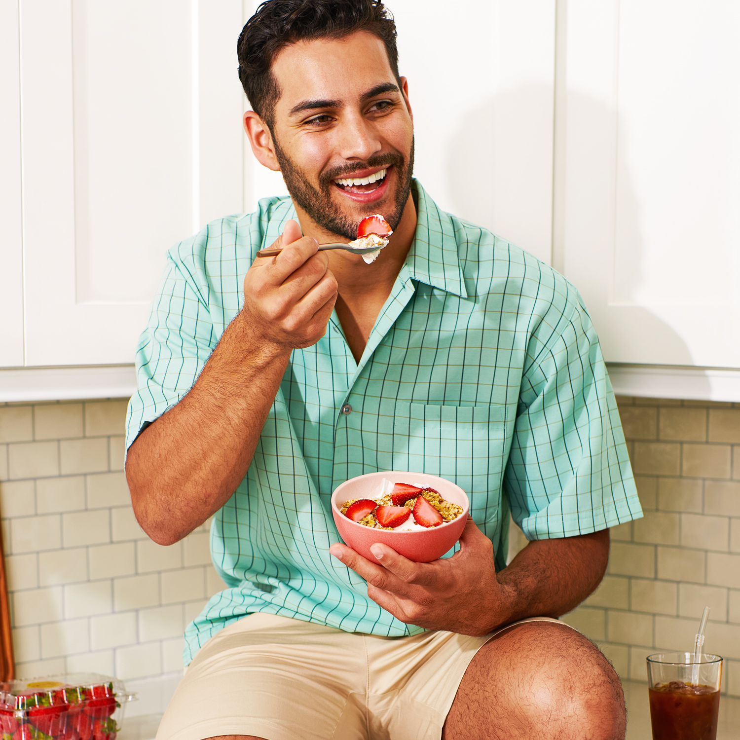 Image of man eating yogurt with fresh sliced strawberries and granola